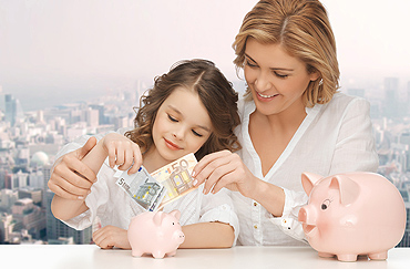 Woman and child adding money to piggy bank.